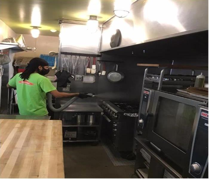 technician with disinfecting spray in commercial kitchen