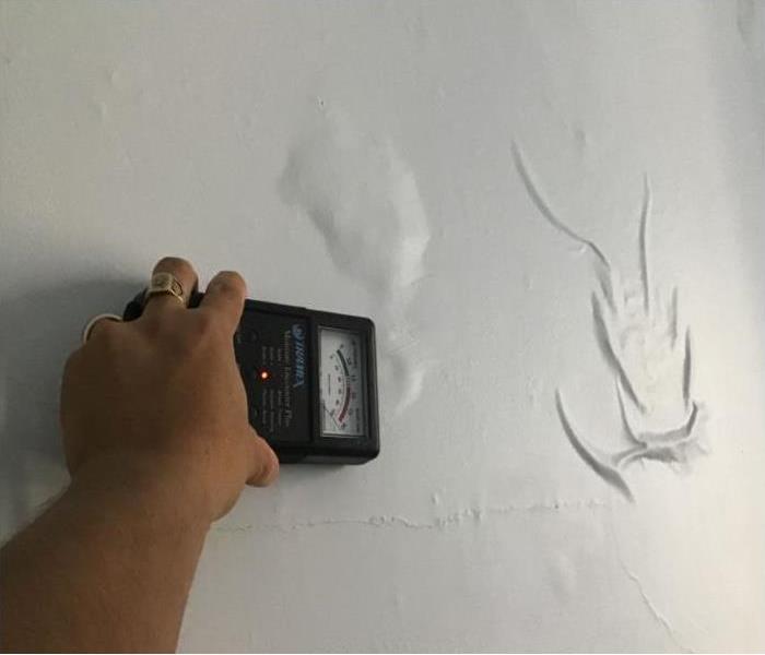 moisture meter against wall in home