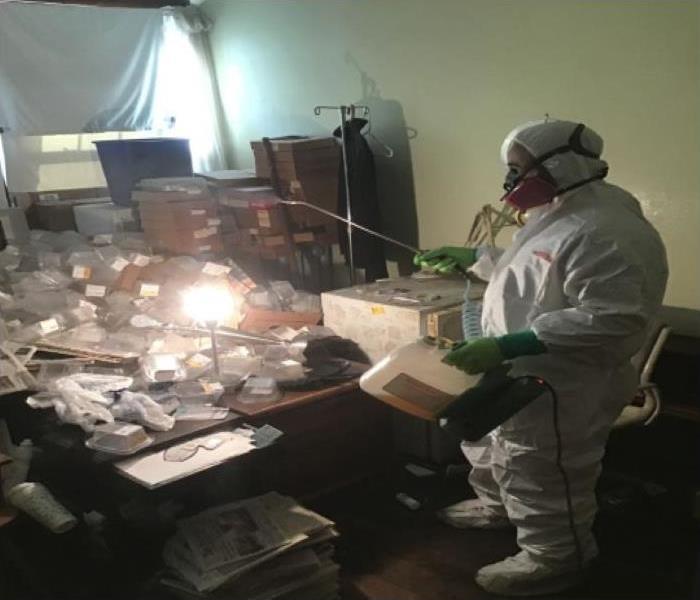 Technicians are in protective suit applying antimicrobial in biohazard area