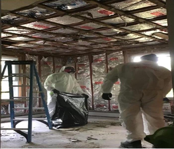 technicians removing drywall debris from room
