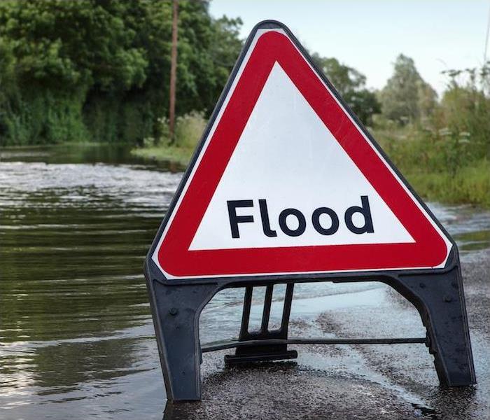 a street completely submerged in water and a flood warning sign in roadway