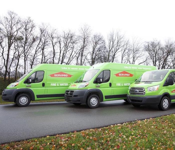 three green SERVPRO trucks lined up on a side street