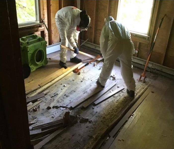 Suited technicians removing flooring